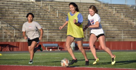 Senior Julia Freeborn attacks the goal during a drill in attempt to score. Sophomore Sadie Eidson and Jinior Ana Iglesies Chirinos follow close behind close behind trying to defend their goal.