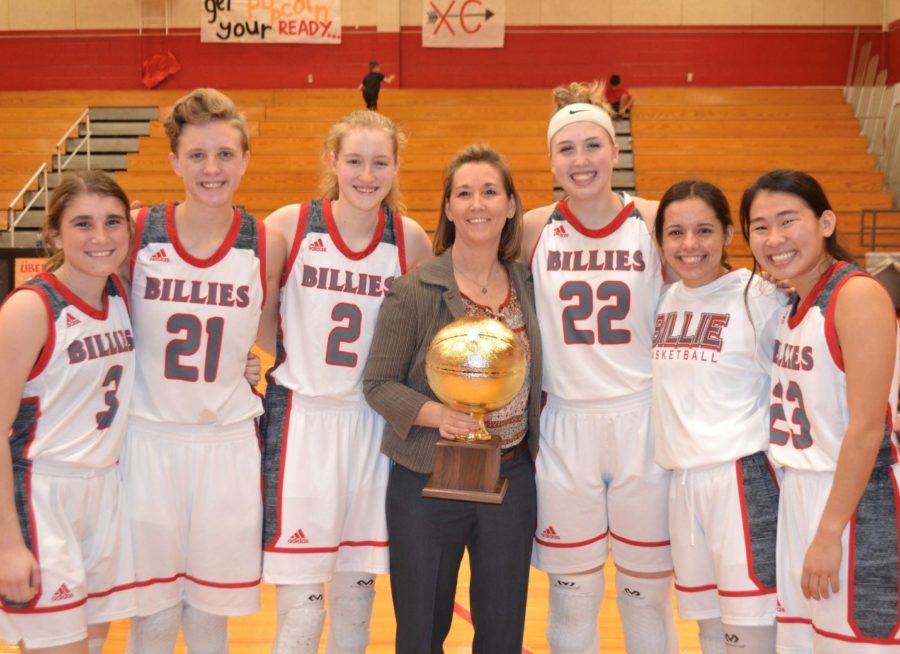 Carrie Grona, girls’ varsity basketball coach, poses with her senior players after winning their last district game against Llano. They went undefeated in district and head to playoffs.
