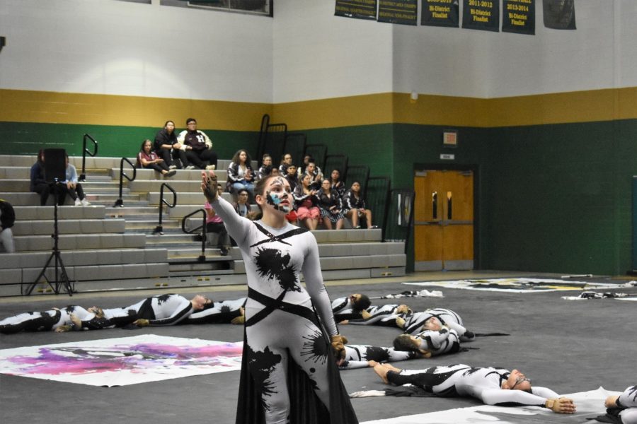 Katie Robertson with other color guard members behind her performing at competition.  